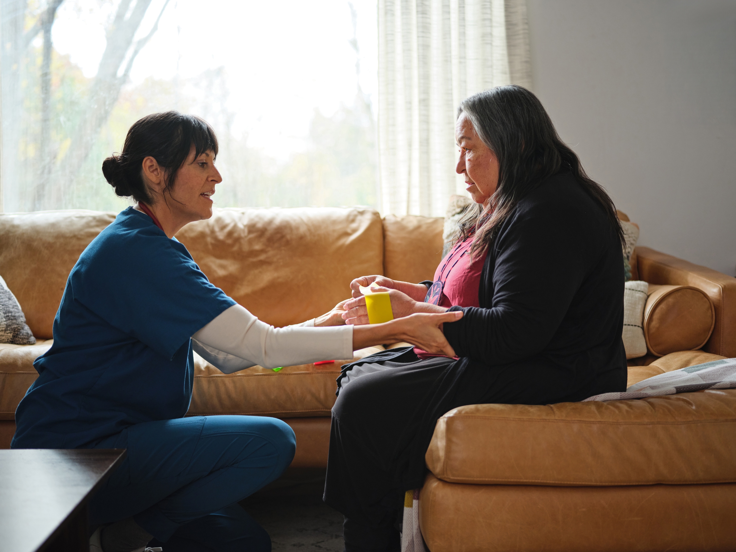 Native American elder woman exercises with resistance bands on couch