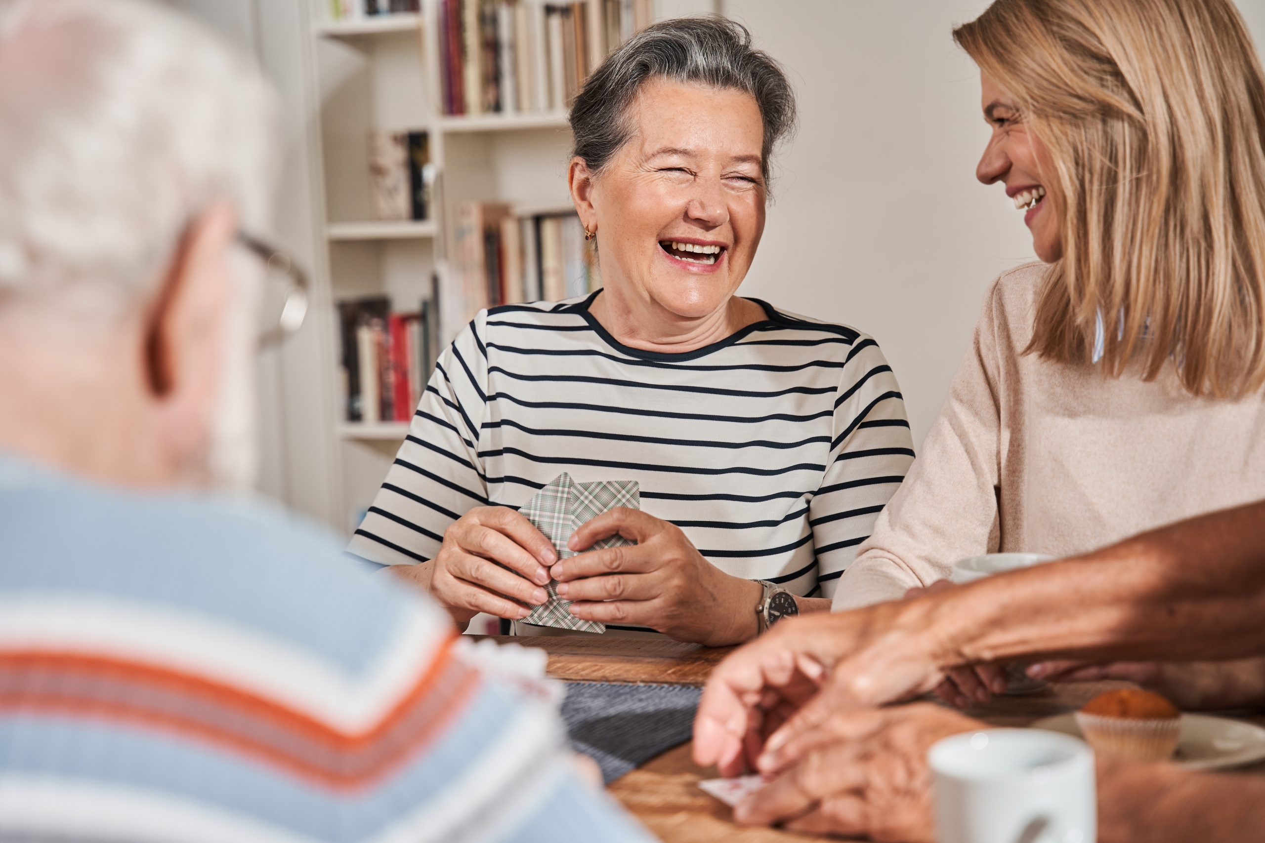 Senior woman laughing out loud while sitting at the table with her caregiver